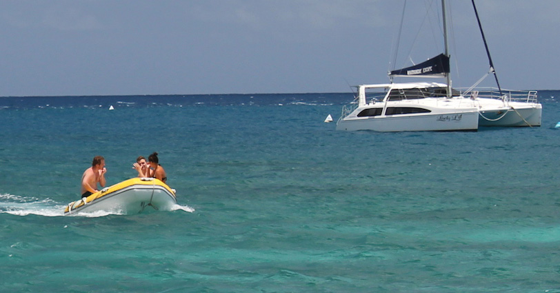 dinghy-with-couple-on-board-near-catamaran-crop