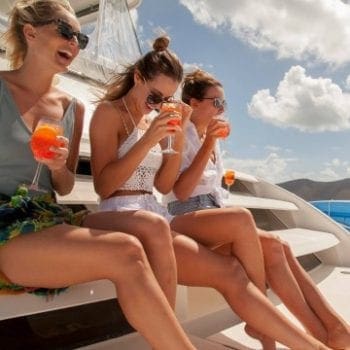 Three girls enjoying a cocktail on the front of a power catamaran