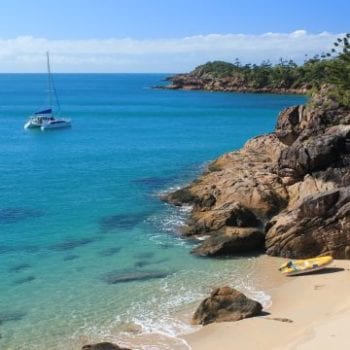 A sailing catamaran anchored at Thomas Island with a tender on the beach