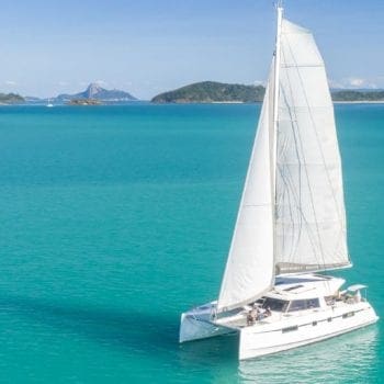 A drone shot of a sailing catamaran and crew relaxing on deck