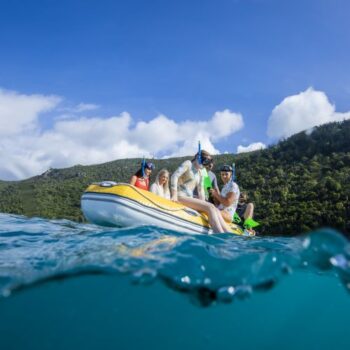 A group of adults and teenagers in an inflatable dinghy, wearing snorkel gear